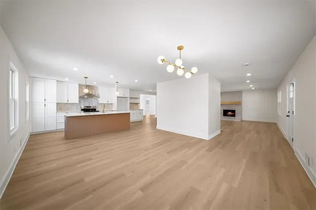 a large kitchen with kitchen island a stove a refrigerator a sink and white cabinets with wooden floor