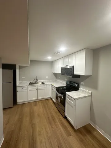 a kitchen with stainless steel appliances white cabinets and wooden floor