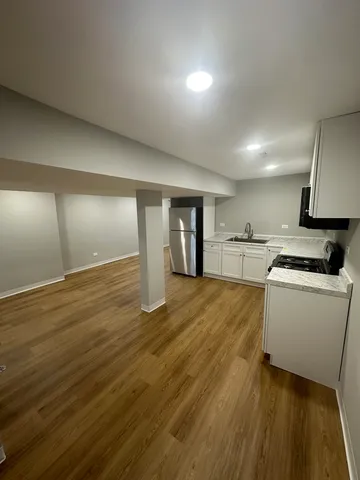 a view of kitchen and empty room with wooden floor