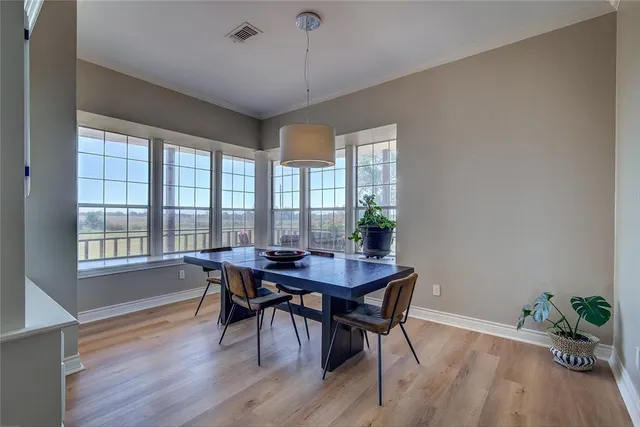 a dining room with wooden floor a chandelier a wooden table and chairs