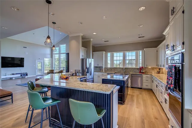 a dining room with stainless steel appliances kitchen island granite countertop a dining table chairs and a view of living room