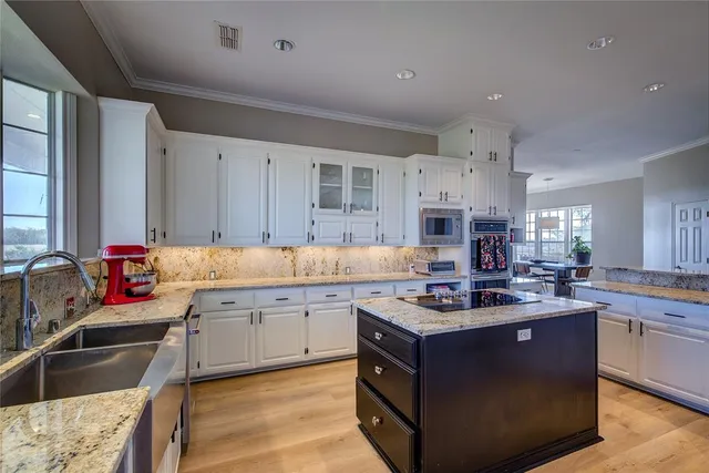 a kitchen with kitchen island granite countertop a sink stove and cabinets