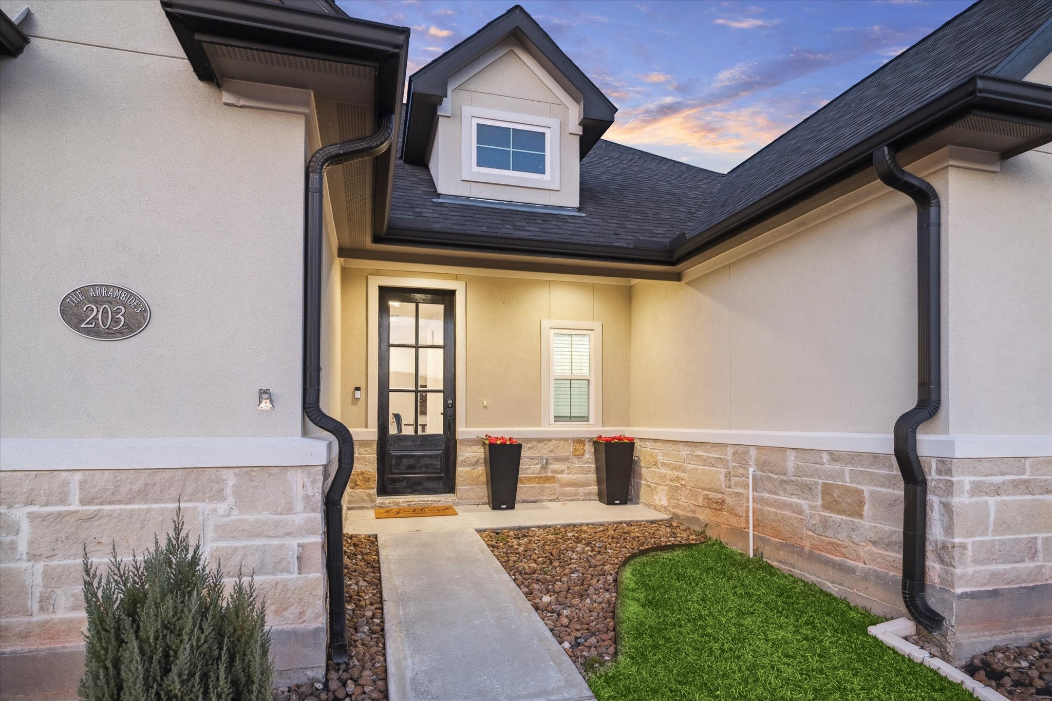 203 Hampton Glen Road Montgomery, TX 77356 - Photo 4 of 35 Welcome home to 203 Hampton Glen Road in the prestigious, private gated community of Bentwater on Lake Conroe. A closer look at the welcoming front entry of this beautiful home. Curb appeal shines with a landscaped walkway, elegant black planters, and a charming dormer window that adds character to the façade. Step inside to discover a bright, open layout ideal for both everyday living and entertaining.