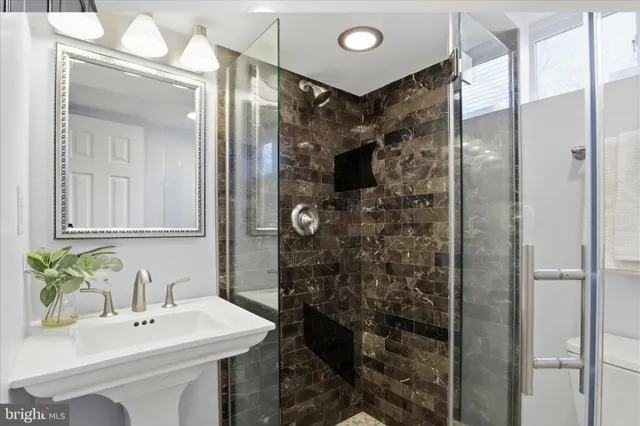 a bathroom with a sink shower and a mirror