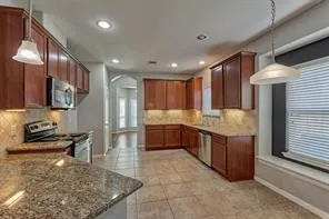 a kitchen with stainless steel appliances granite countertop a stove a sink and a refrigerator