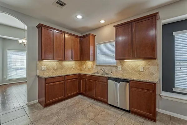 a kitchen with granite countertop stainless steel appliances wooden cabinets and a sink
