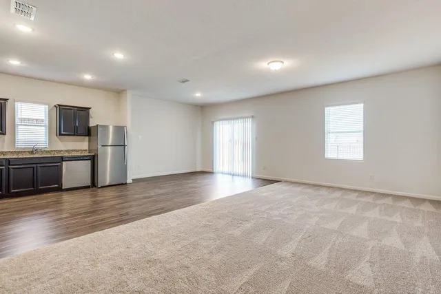 a open kitchen with stainless steel appliances granite countertop a refrigerator and a stove top oven