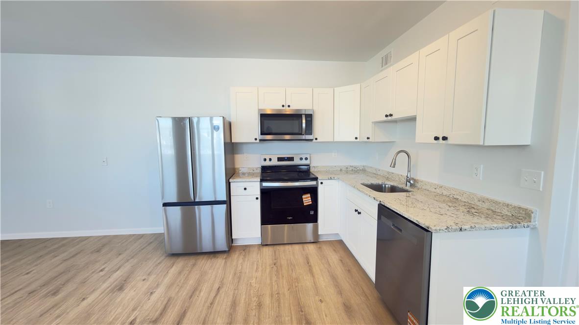 403 North Walnut Street, Unit D Bath, PA 18014 - Photo 6 of 17 a kitchen with a refrigerator sink and white cabinets