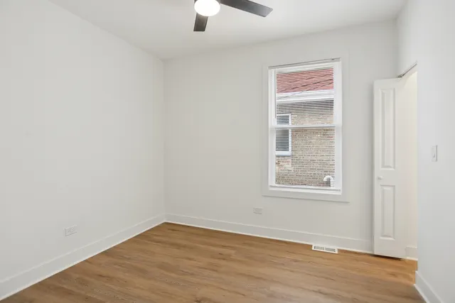 an empty room with wooden floor cabinet and windows