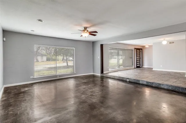 a view of an empty room with window and wooden floor