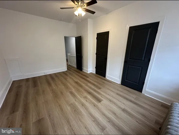 a view of an empty room with wooden floor and closet