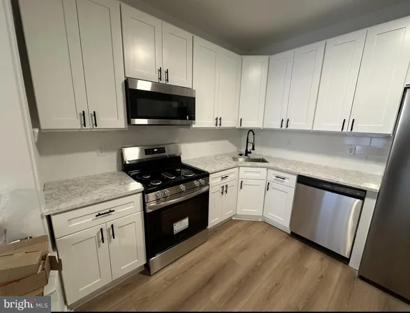 a kitchen with granite countertop white cabinets sink and stainless steel appliances