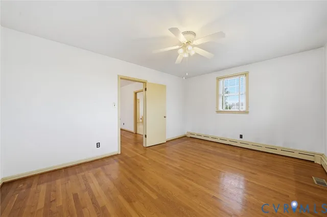 an empty room with wooden floor closet and windows
