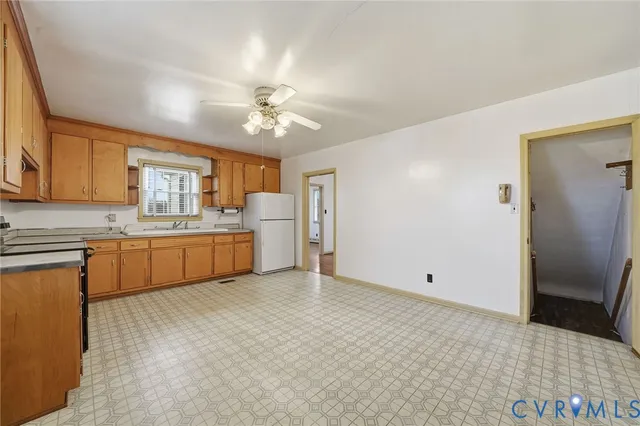 a large white kitchen with a sink and dishwasher a refrigerator with wooden floor