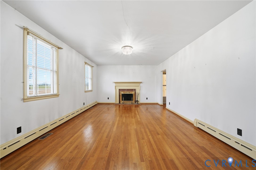 6726 Newtown Road St. Stephens Church, VA 23148 - Photo 27 of 50 an empty room with wooden floor fireplace and windows