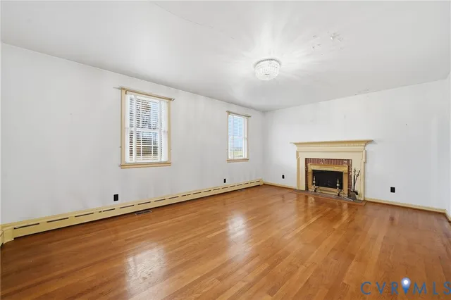 an empty room with wooden floor and fireplace
