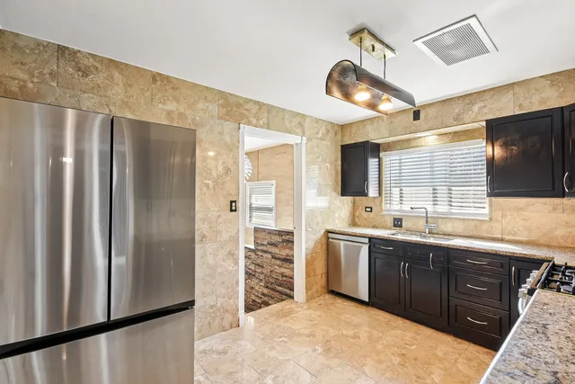 a kitchen with stainless steel appliances granite countertop a refrigerator and a sink