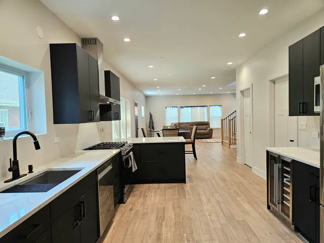 a large kitchen with stainless steel appliances a sink dishwasher a oven and a dining table with wooden floor