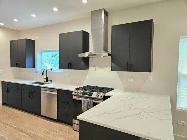 a kitchen with stainless steel appliances a sink a stove a refrigerator and cabinets