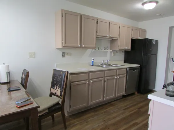 a kitchen with stainless steel appliances a white table chairs and a refrigerator