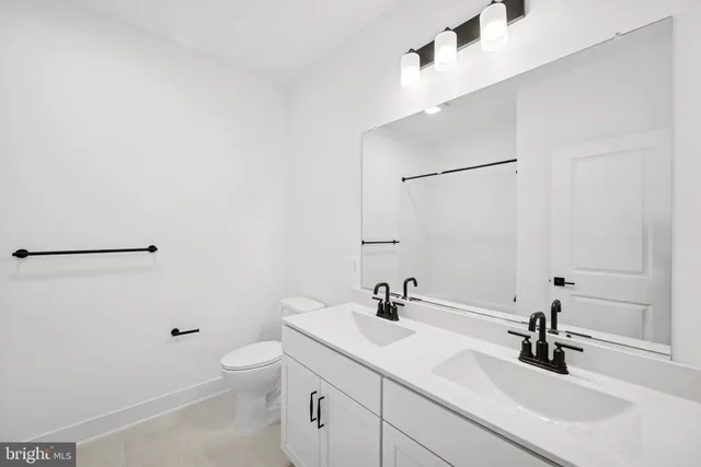 a bathroom with a sink a toilet and a large mirror