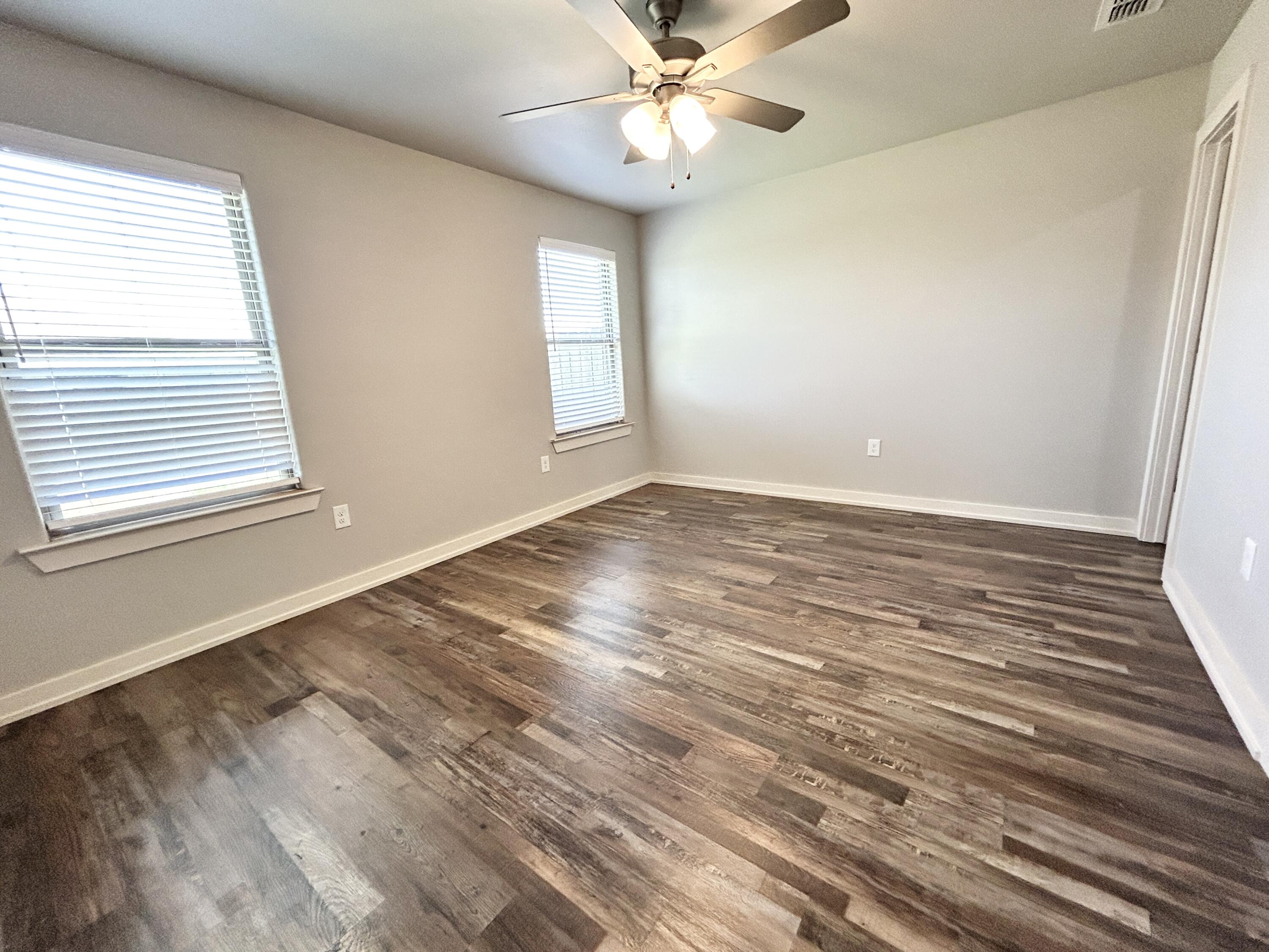 5512 122nd Street, Unit B Lubbock, TX 79424 - Photo 7 of 9 a view of an empty room with wooden floor and a window