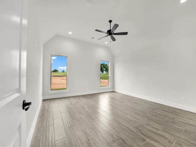 a view of empty room with wooden floor and fan