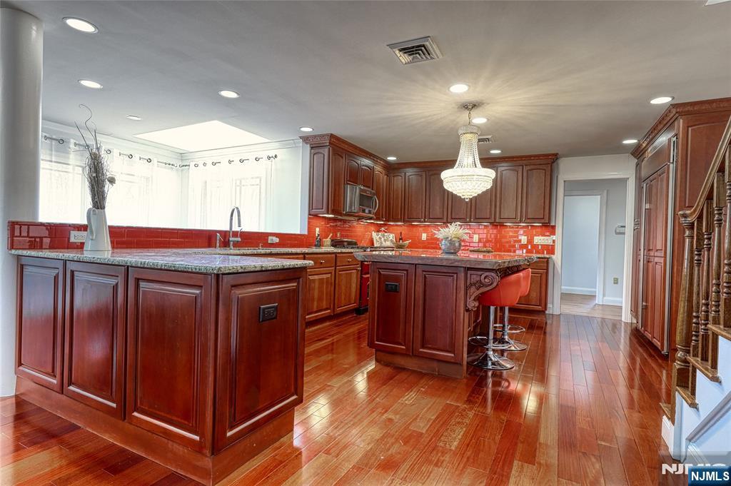 91 Chestnut Ridge Road Saddle River, NJ 07458 - Photo 14 of 41 a kitchen with stainless steel appliances granite countertop a stove a sink dishwasher and a dining table with wooden floor