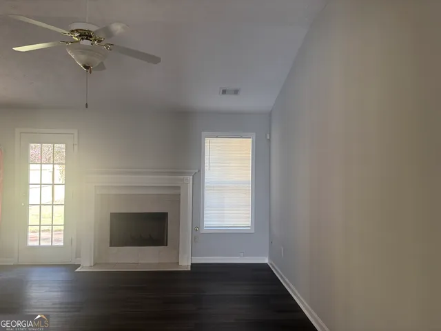 a view of an empty room with wooden floor fireplace and a window
