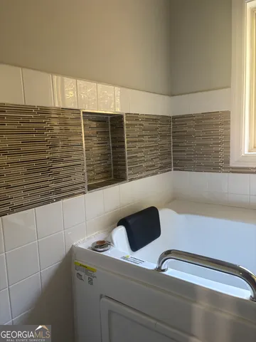 a bathroom with a granite countertop sink a bathtub and next to a window