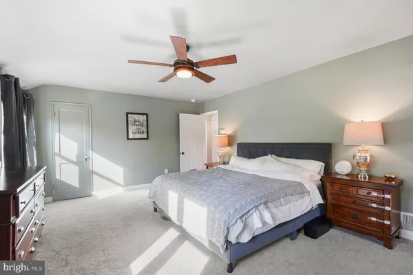 a spacious bedroom with a bed a dresser and a chandelier