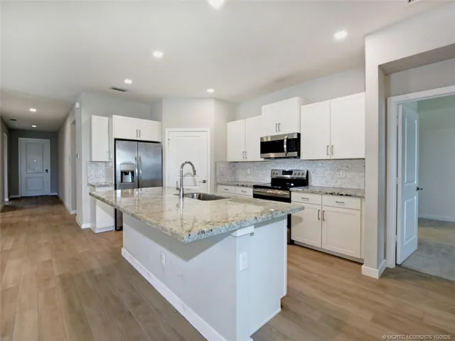 a kitchen with stainless steel appliances granite countertop a sink a stove and microwave with wooden floor