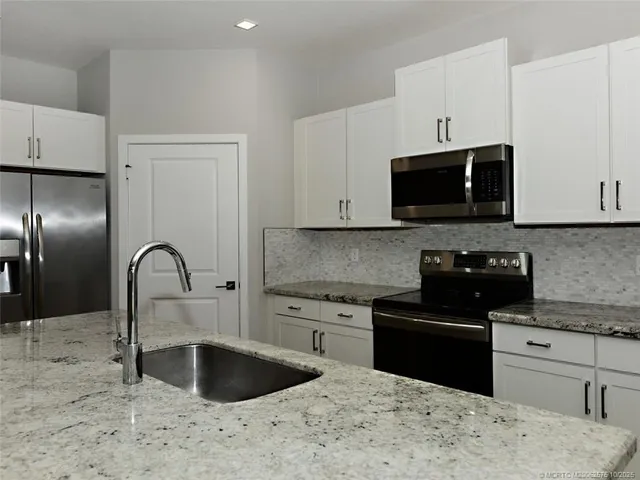 a view of a kitchen with refrigerator and white cabinets