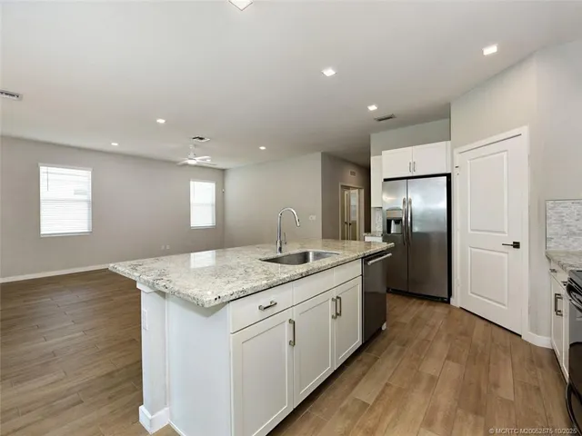 an empty room with wooden floor ceiling fan and windows
