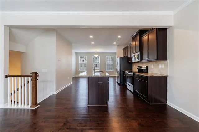 a kitchen with stainless steel appliances granite countertop a refrigerator a stove top oven a sink and dishwasher with wooden floor