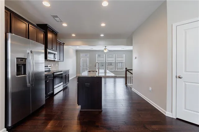 a kitchen with stainless steel appliances granite countertop a refrigerator and a wooden floors