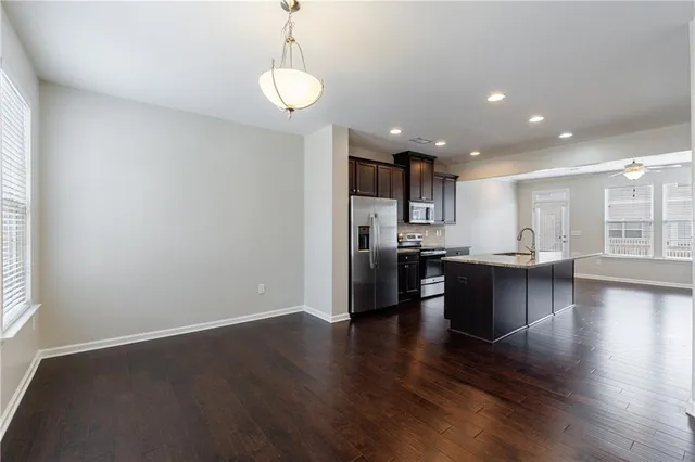 an open kitchen with a refrigerator and wooden floor