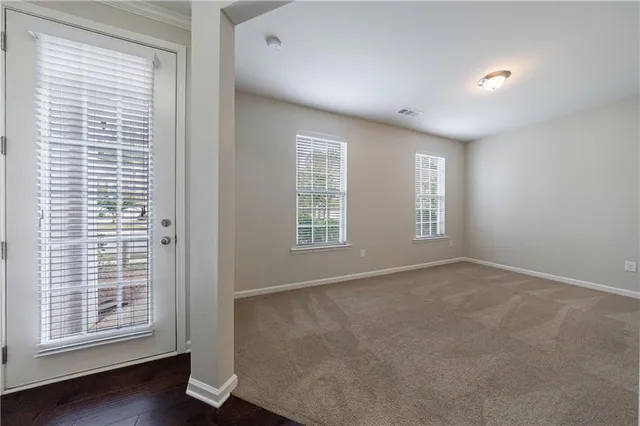 a view of an empty room with a window and wooden floor