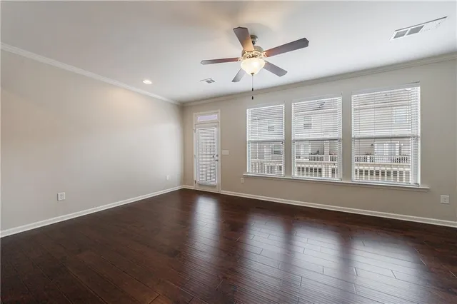 an empty room with wooden floor fan and windows