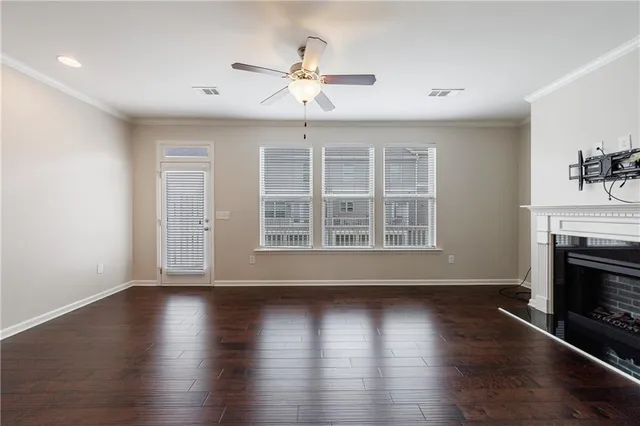 a view of an empty room with wooden floor fireplace and a window