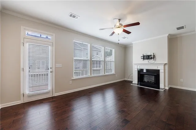 a view of an empty room with wooden floor fireplace and a window