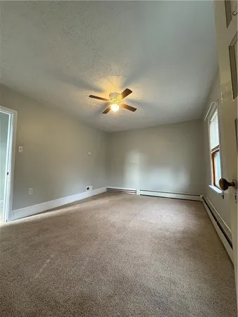 an empty room with windows and chandelier fan