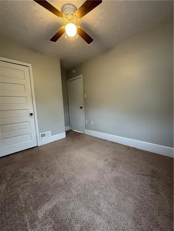 a view of an empty room and chandelier fan