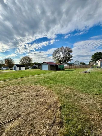 a view of a big yard with plants and large trees