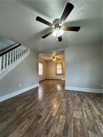 a view of an empty room with a window and wooden floor