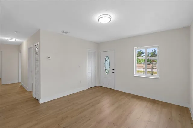 a view of an empty room with wooden floor and a window