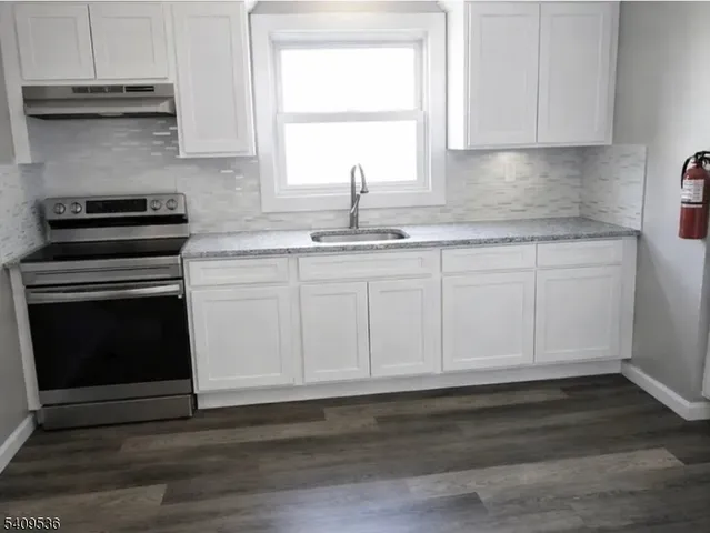 a kitchen with granite countertop white cabinets and a stove