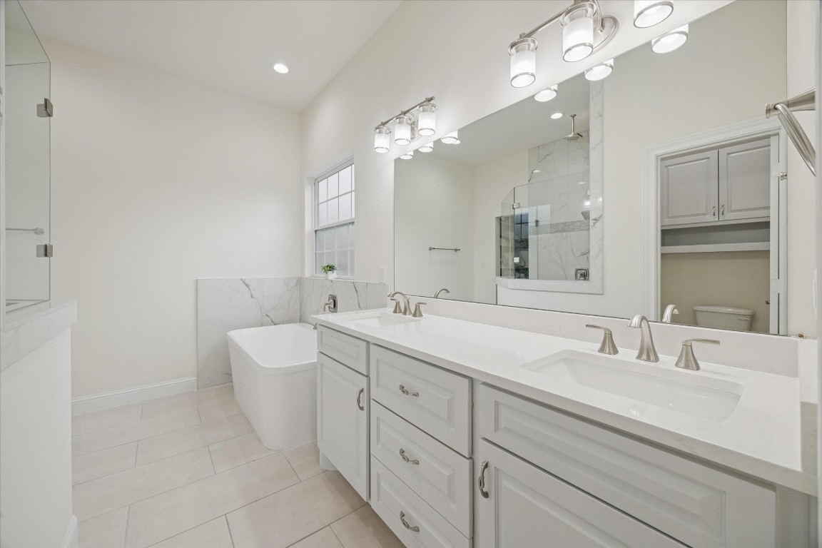 532 Carrell Street Tomball, TX 77375 - Photo 15 of 28 This spacious primary bathroom offers abundant cabinetry and storage, double sinks, elegant LED light fixtures, and a modern soaking tub. Thoughtfully selected tones enhance a peaceful, spa-like atmosphere ideal for relaxation.