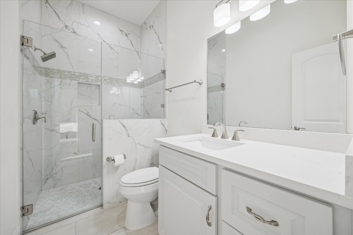 532 Carrell Street Tomball, TX 77375 - Photo 19 of 28 The secondary bathroom offers a spacious shower with frameless glass and real marble walls, a large vanity with ample storage, and modern LED light fixtures. Thoughtfully designed, this space provides comfort and elegance consistent with the rest of the home.