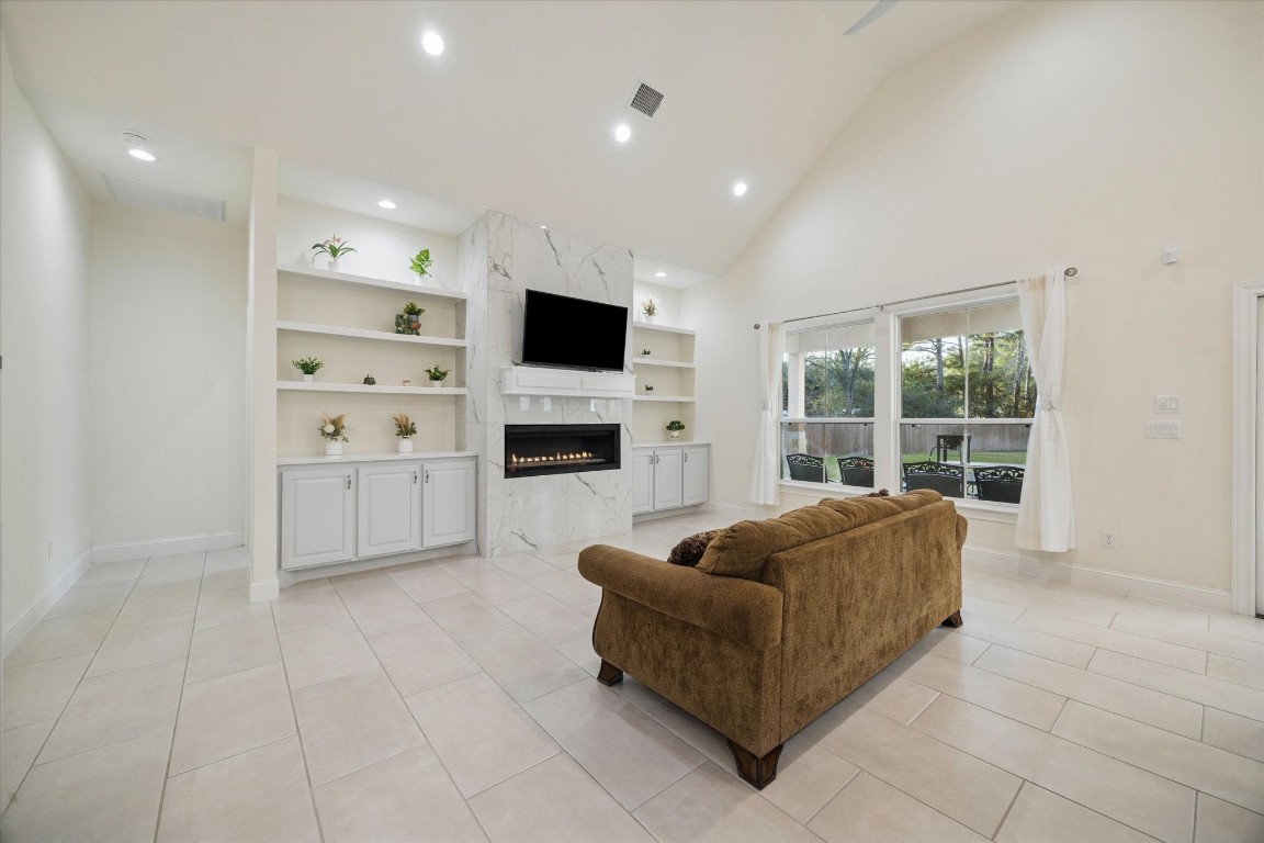 532 Carrell Street Tomball, TX 77375 - Photo 6 of 28 A closer view highlights the fireplace, accented by marble tile. This inviting space is ideal for gatherings and relaxation, filled with natural light from multiple windows that frame backyard views and create a bright, airy atmosphere.
